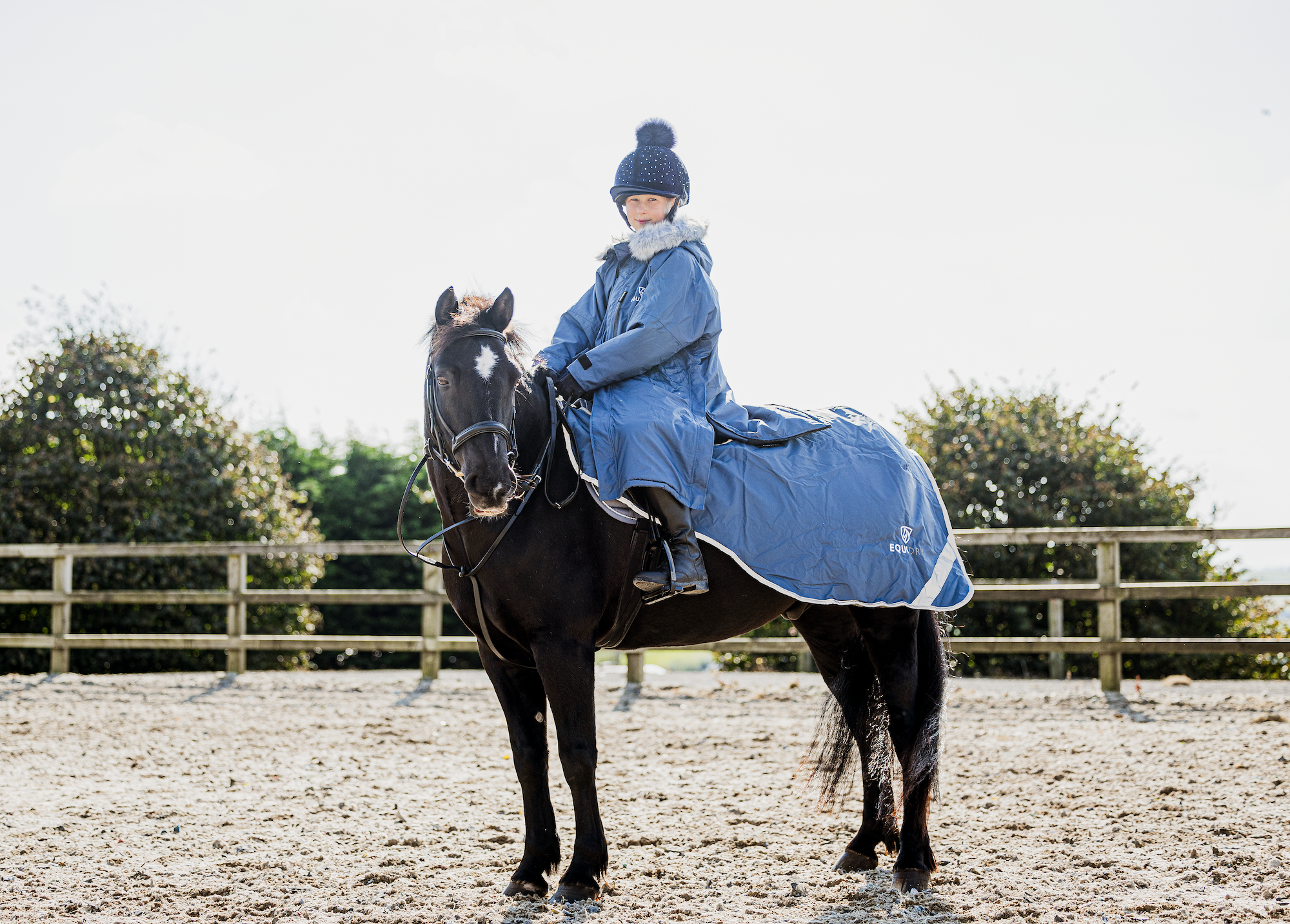 EQUIDRY Evolution Lux children's Warm Waterproof Winter Horse Riding Coat Thick Fleece Lining with Faux Fur Trim Hood being shown in steel blue on horse