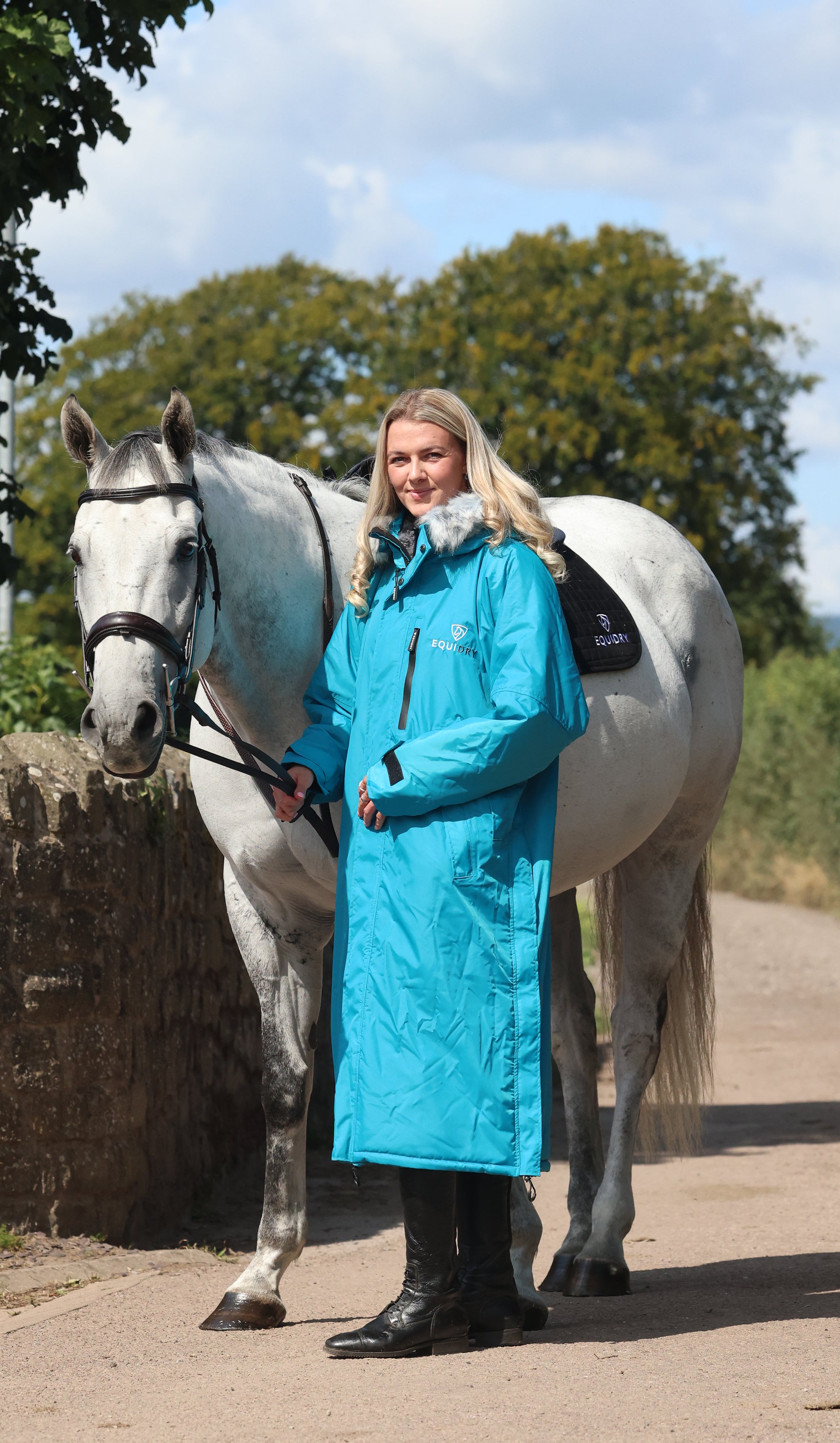 EQUIDRY Evolution Lux Women's Warm Waterproof Winter Horse Riding Coat Thick Fleece Lining with Faux Fur Trim Hood in turquoise rider full front view with horse 