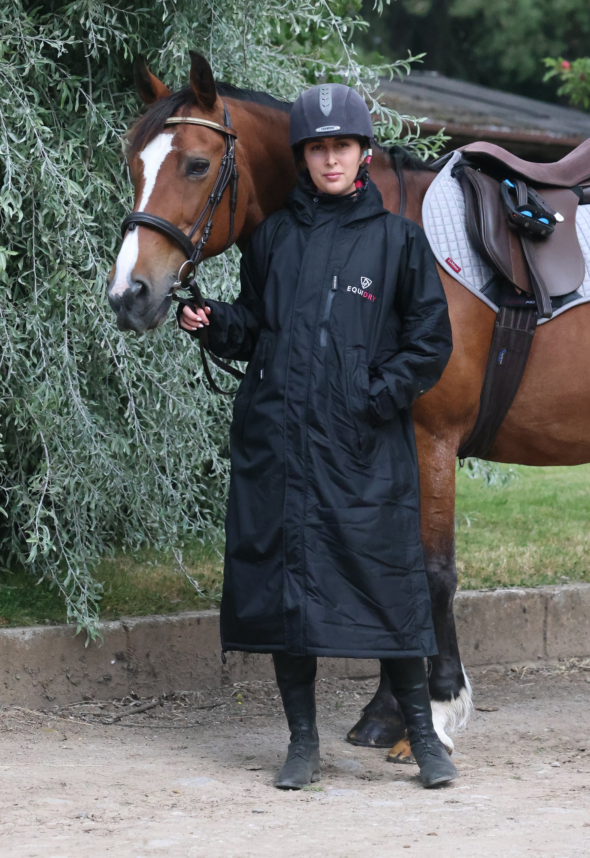 EQUIDRY women's long waterproof horse riding coat in black/peacock pink shown by rider with horse