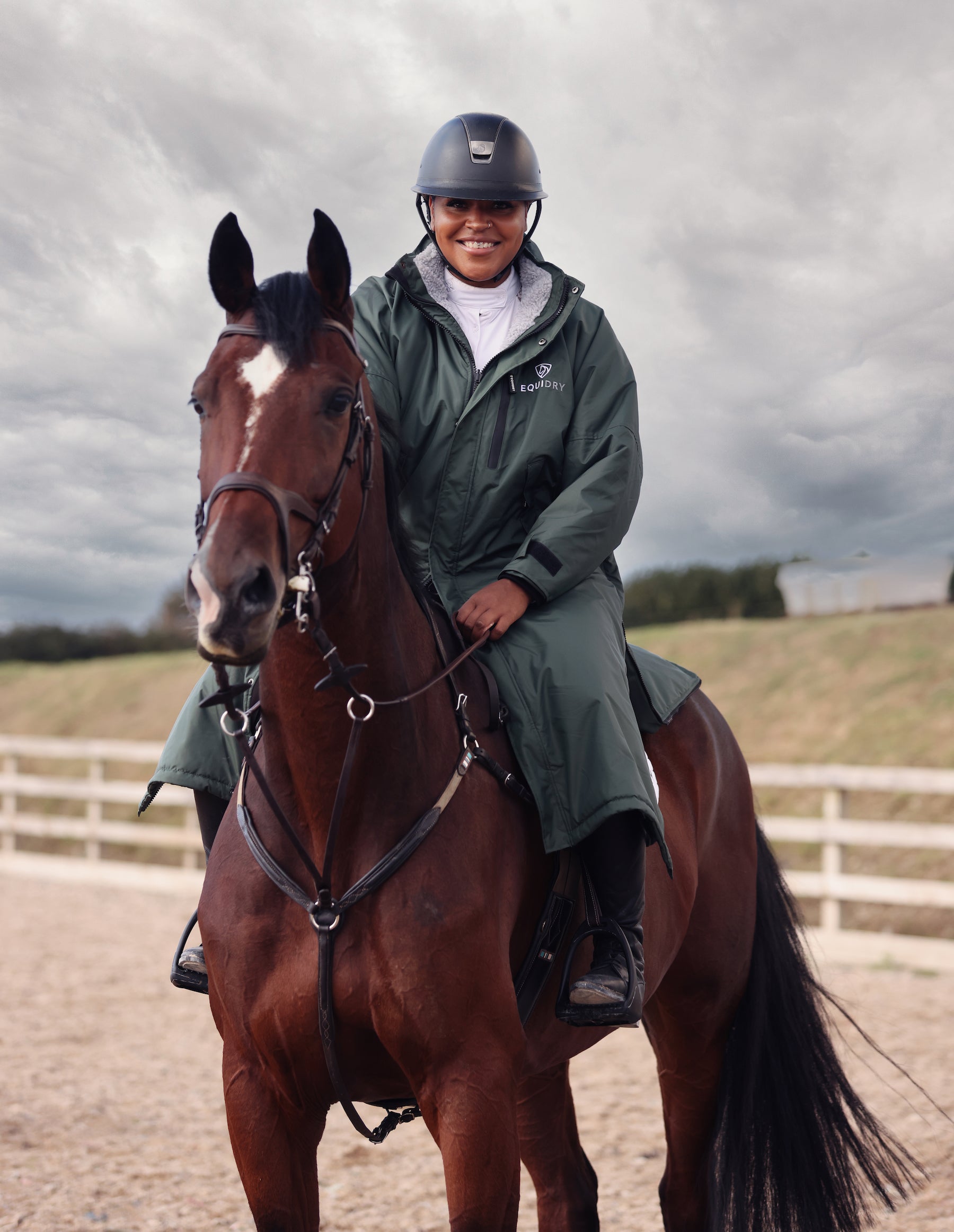 EQUIDRY Evolution Pro women's Warm Waterproof Horse Riding Coat Thick Fleece Lining Stowaway Hood in black forest green modelled by rider at a show on horseback 