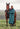 EQUIDRY women's long waterproof horse riding coat in Teal/Peacock Pink modelled by rider stood with horse 