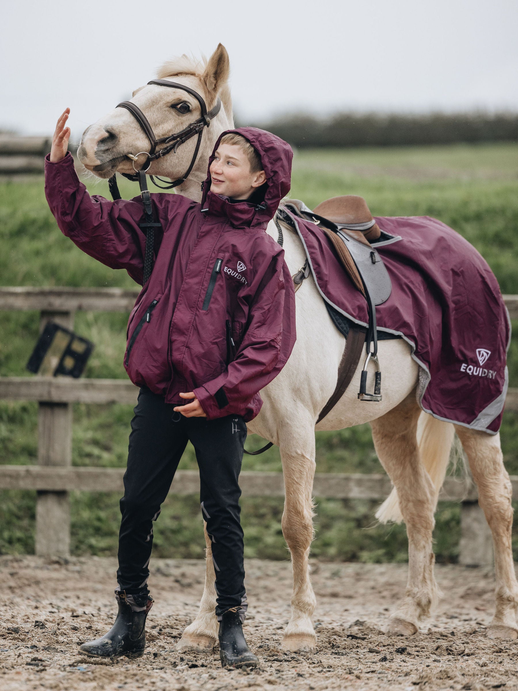 Shortie Child's Oversized Short Waterproof Riding Jacket Thin Fleece Lining Stowaway Hood in plum worn by rider with matching exercise sheet