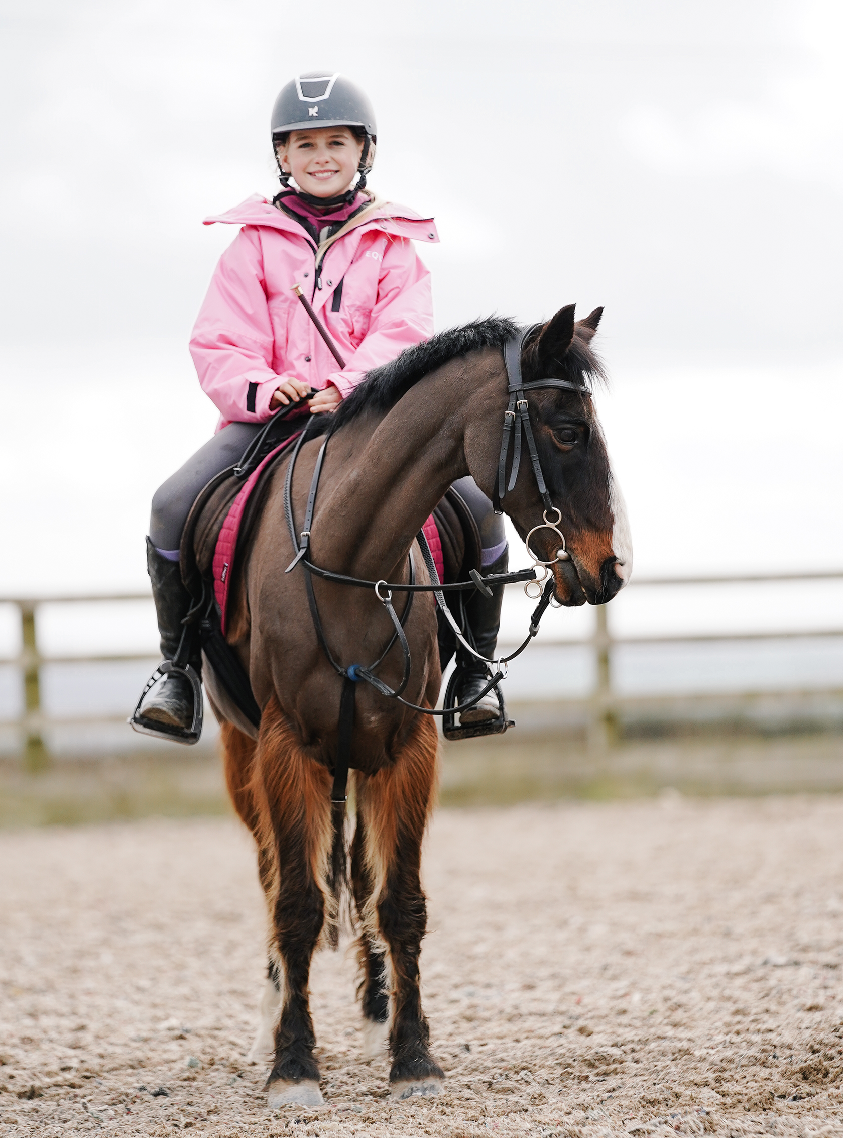 Shortie Child's Oversized Short Waterproof blouson style Riding Jacket Thin Fleece Lining Stowaway Hood in penelope pink shown by child on horse 